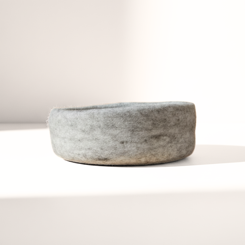 Handmade wool felt medium bowl in marbled beige displayed on light background