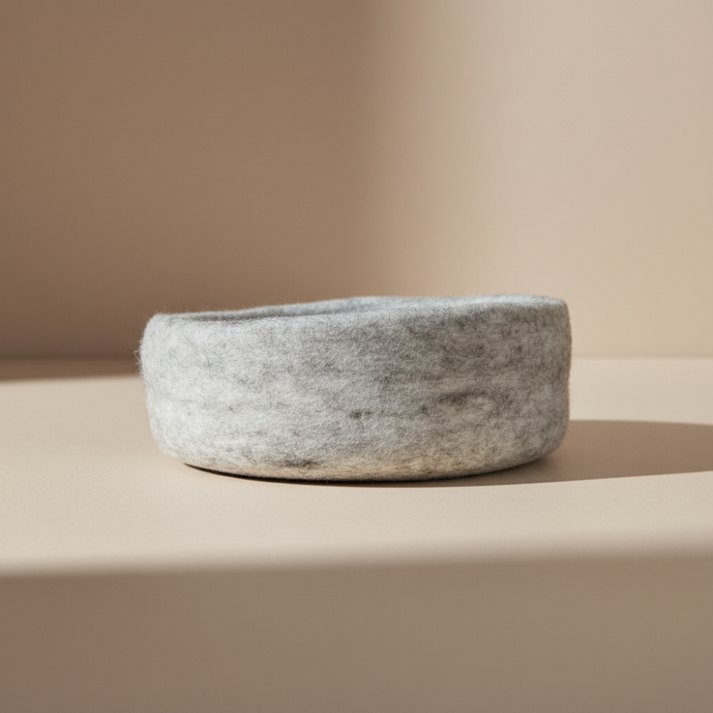 Handmade wool felt medium bowl in marbled beige displayed on light background