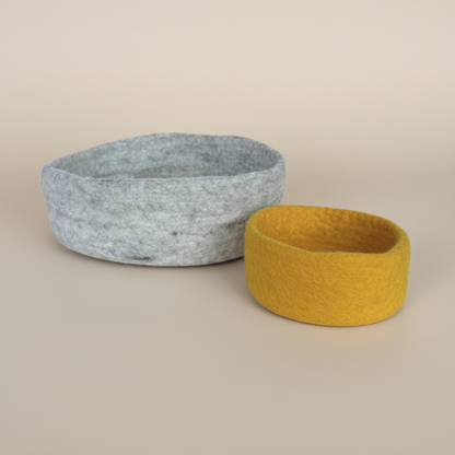 Handmade wool felt nesting bowls- one medium bowl in marbled beige and one small bowl in sunflower yellow, displayed on light background
