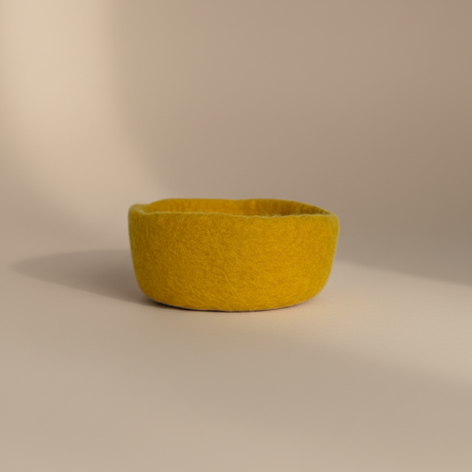 Yellow felt bowl on a beige background