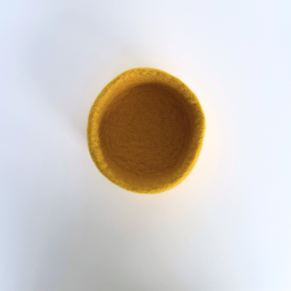 Round yellow felted bowl on a white background