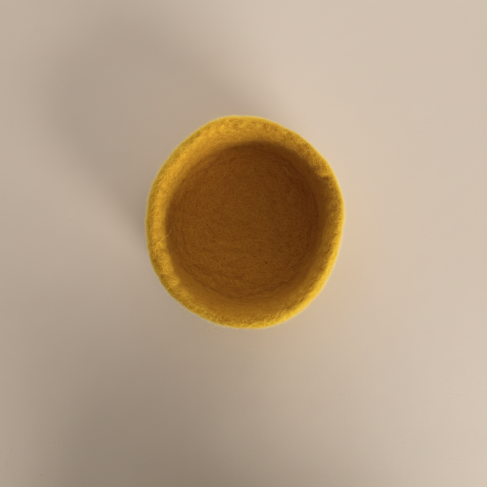 Yellow felt bowl on a beige background