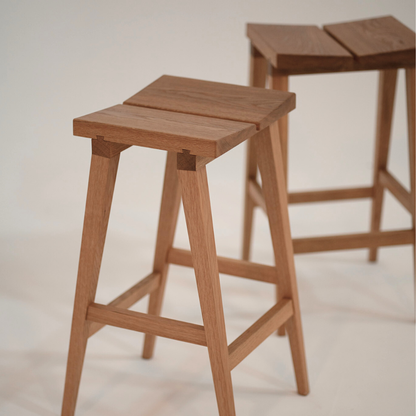 Two wooden bar stools on a light background