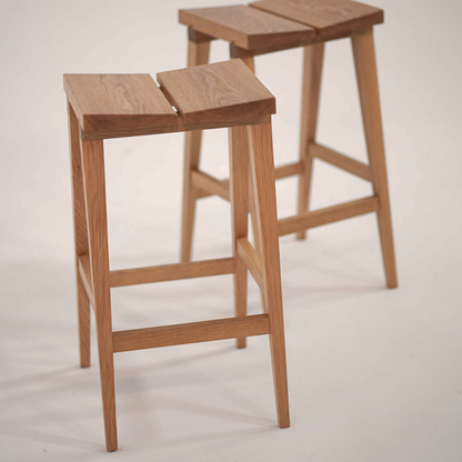Two wooden bar stools on a light grey background
