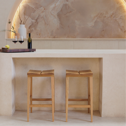 Two wooden bar stools in front of a stone wall with a decorative archway.