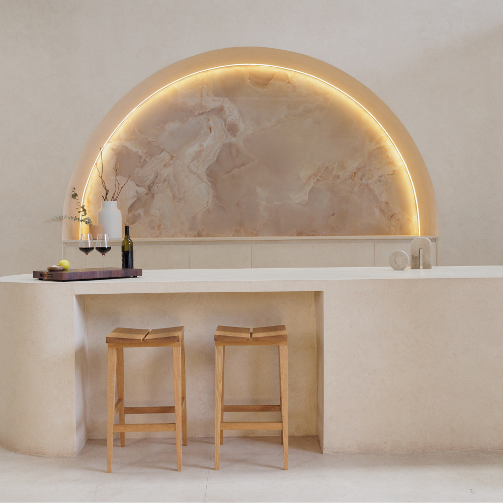 Modern kitchen with marble backsplash, bar stools, and neutral color palette.
