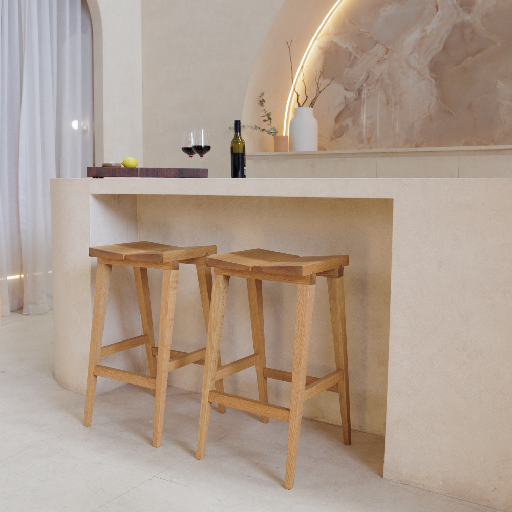 Two wooden bar stools in front of a kitchen counter with decor items.