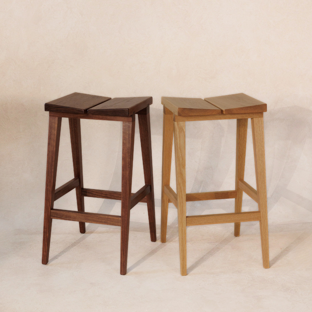 Two wooden bar stools, one walnut and one oak, on a plain background.