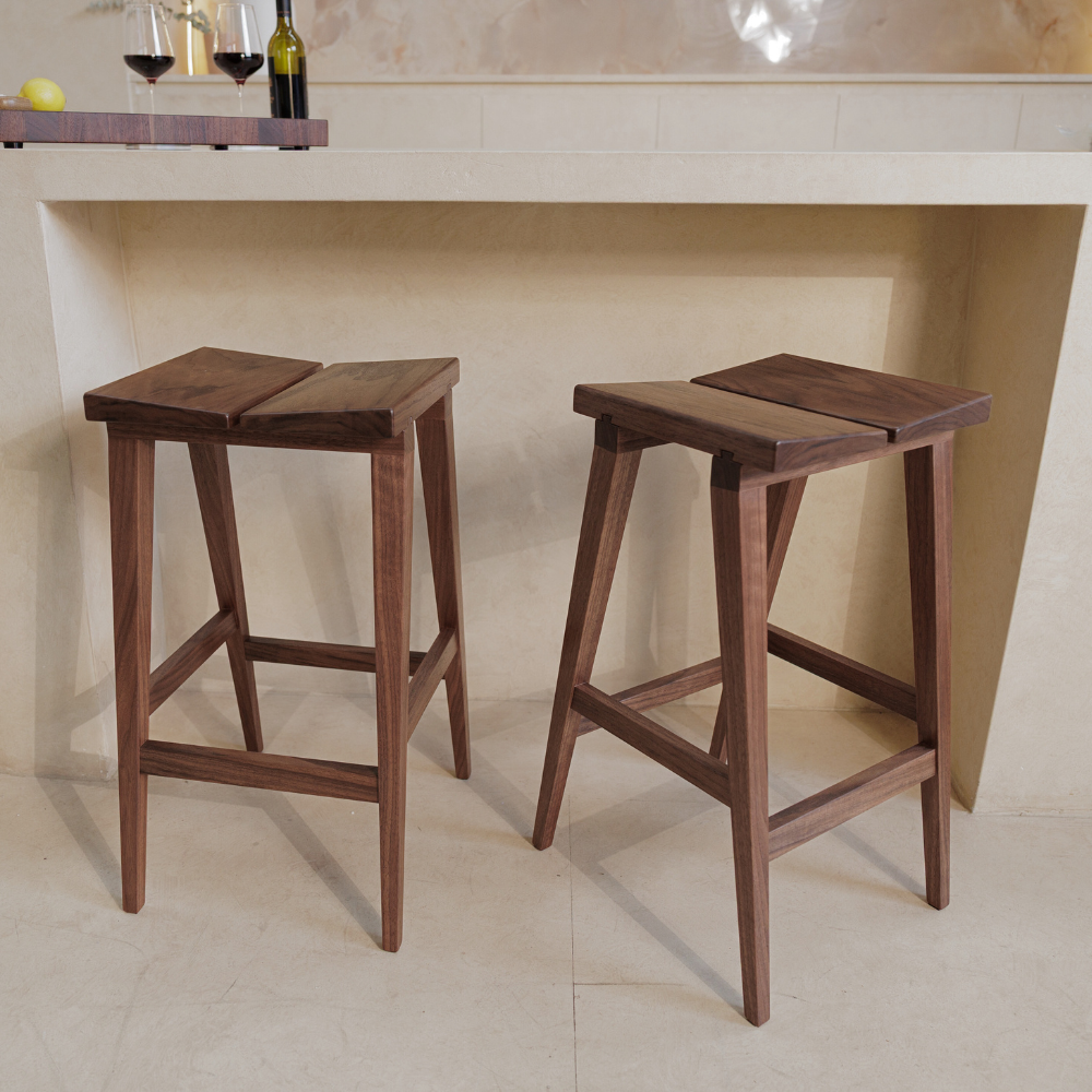 Two wooden bar stools in front of a kitchen counter.