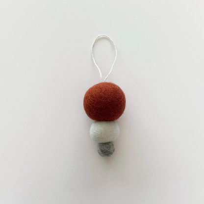 Pebble Studio Nordic Bauble in rust: three stacked felt spheres made from New Zealand wool with a hanging loop.