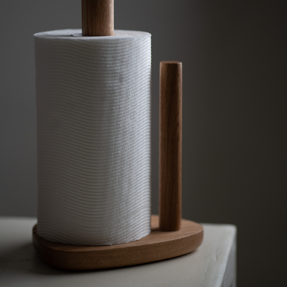 Wooden paper towel holder with a roll of paper towels on a neutral background