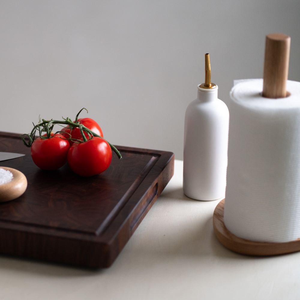 Wooden paper towel holder styled next to a chopping board on a neutral background