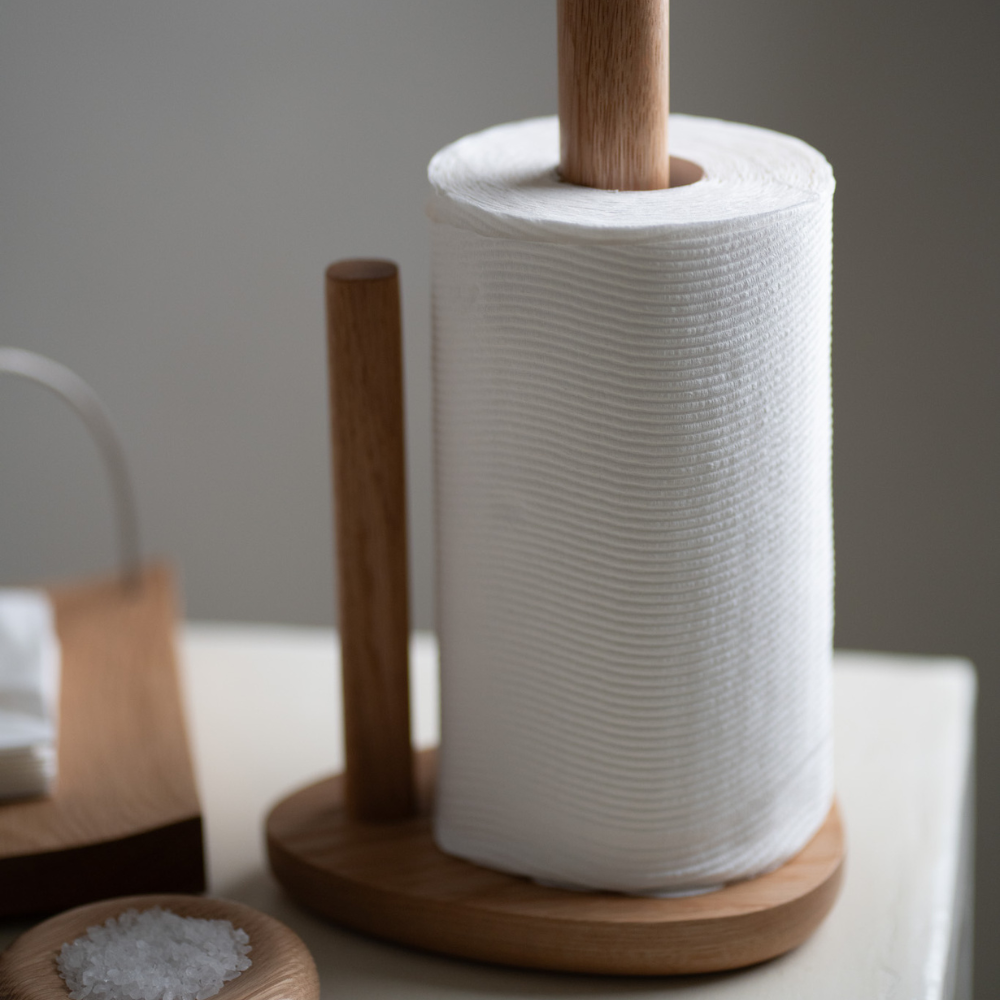 Wooden paper towel holder with a roll of white paper towels on a neutral background