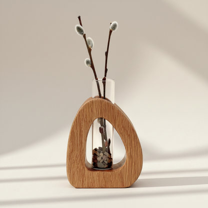 Wooden vase with a clear glass interior containing willow branches on a neutral background
