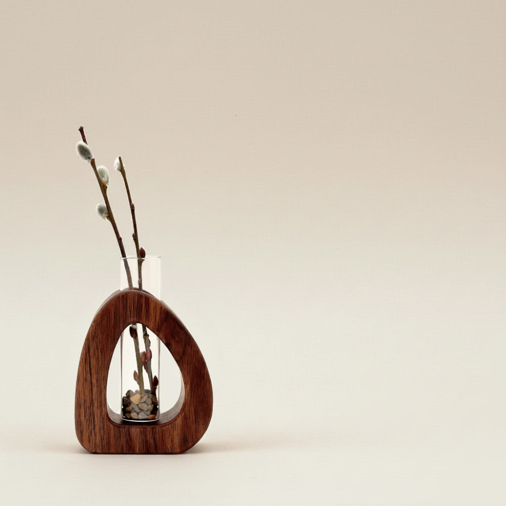 Wooden vase with a glass insert containing willow branches on a beige background