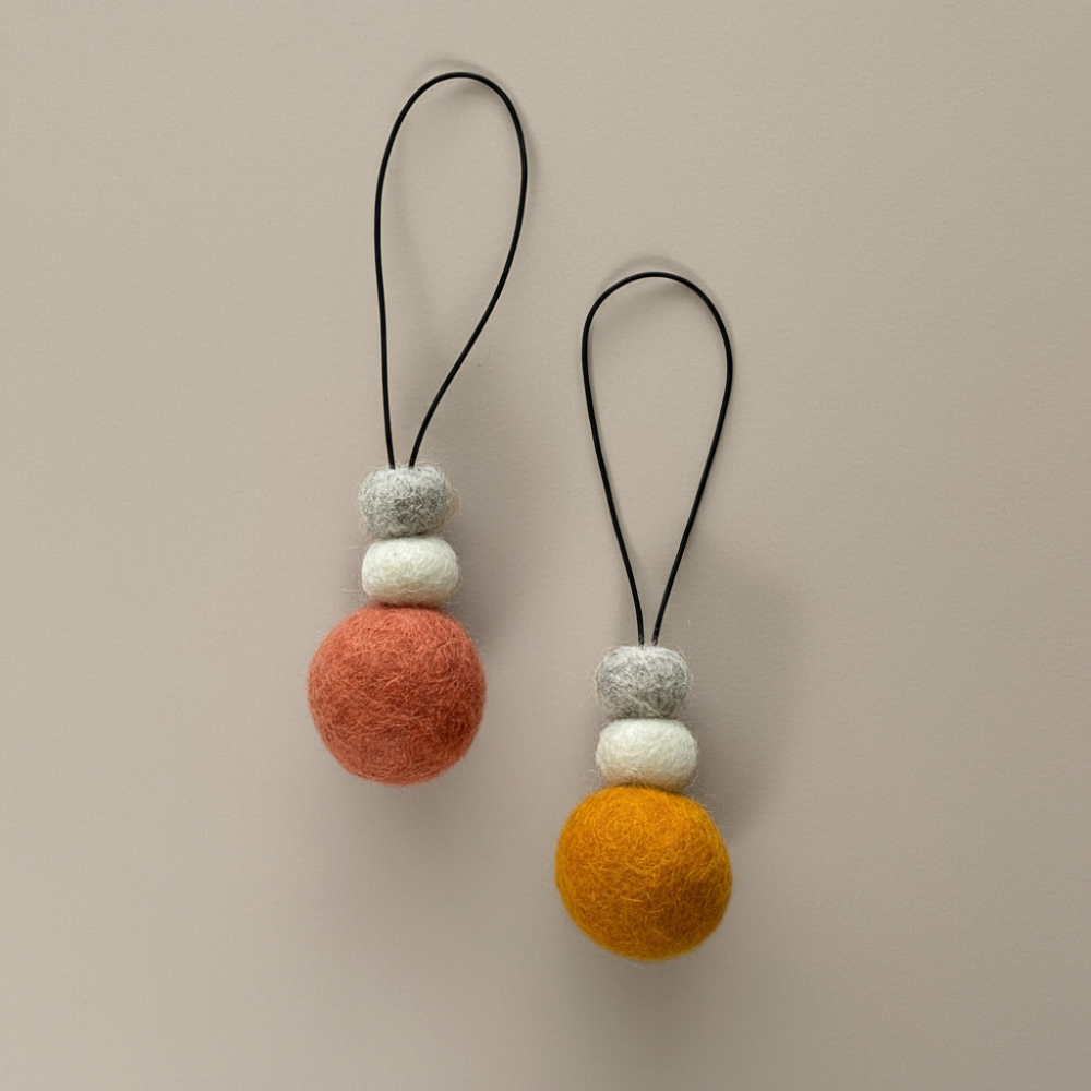 Two hanging wool diffusers on a light colour background.