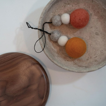 Felted ball hanging decorations with three balls on a textured surface.