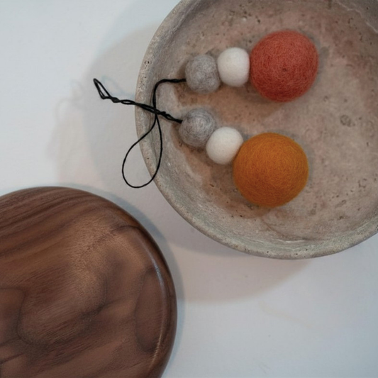 Felted ball hanging decorations with three balls on a textured surface.