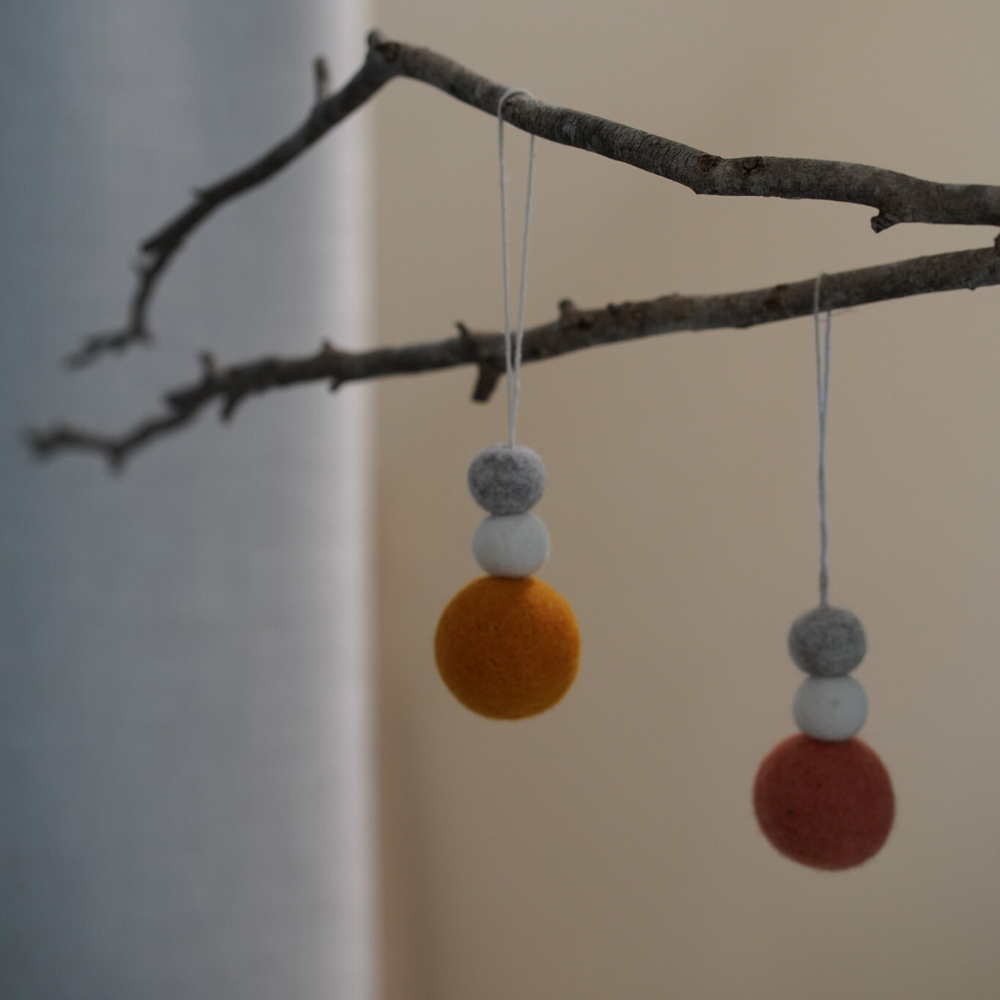 Hanging wool diffusers on a branch against a neutral background