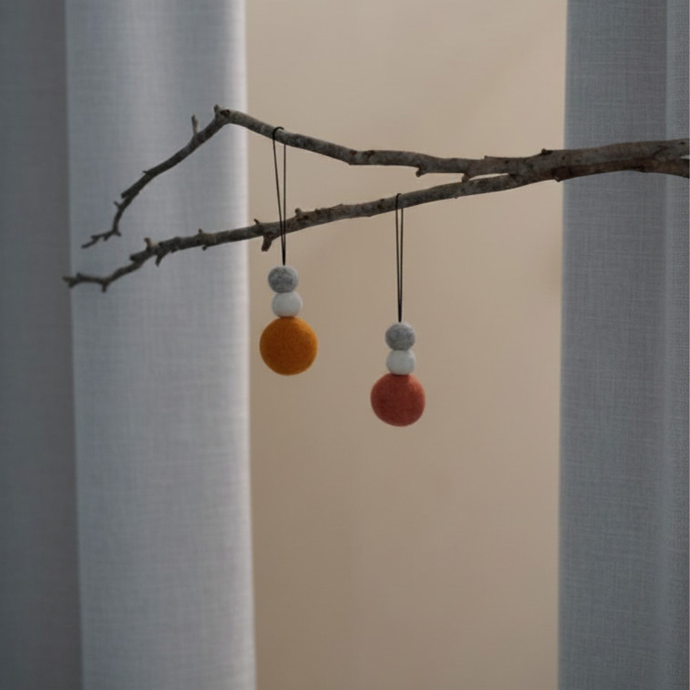Decorative branch with colourful wool decorations against a neutral background