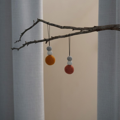 Decorative branch with colourful wool decorations against a neutral background