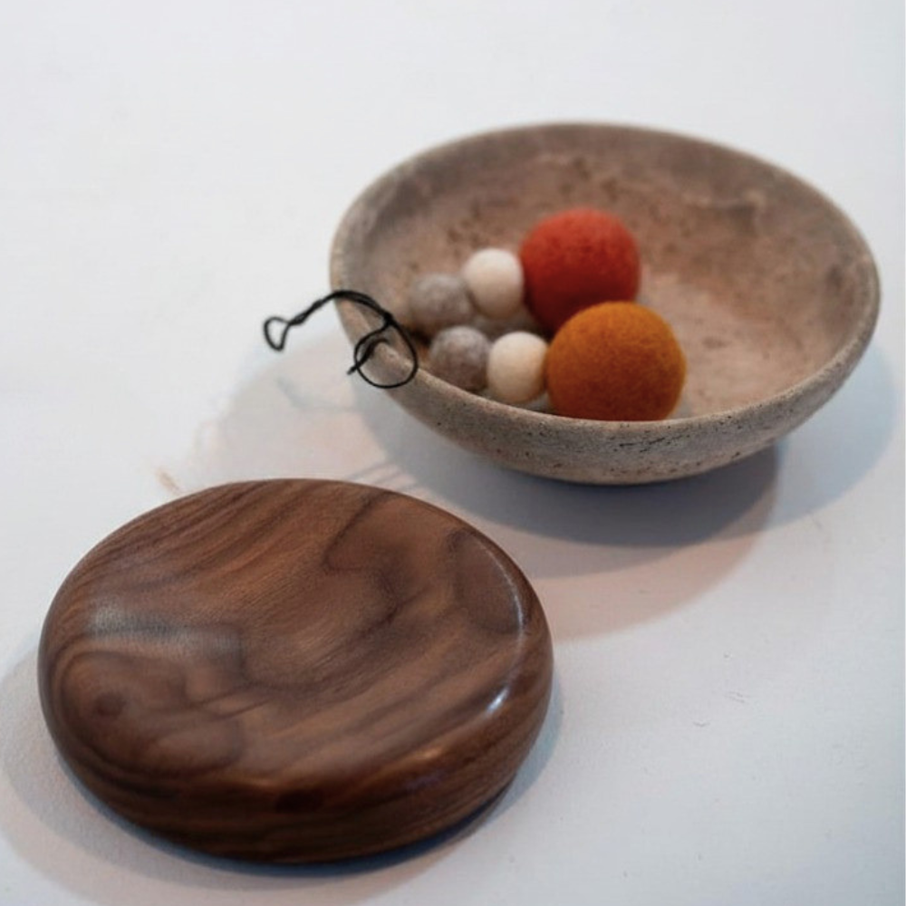 Wool hanging decorations in a travertine bowl on a white background
