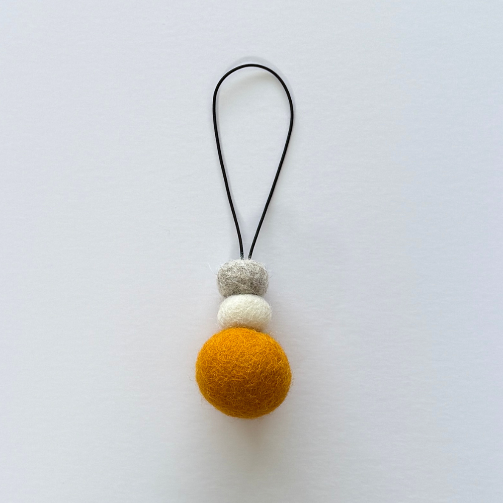 Bright saffron yellow wool hanging diffuser with natural and grey felt accent beads, handcrafted and displayed on white backdrop. Designed for use with essential oils.