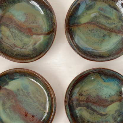 Four ceramic disheswith a multicoloured glaze on a white background
