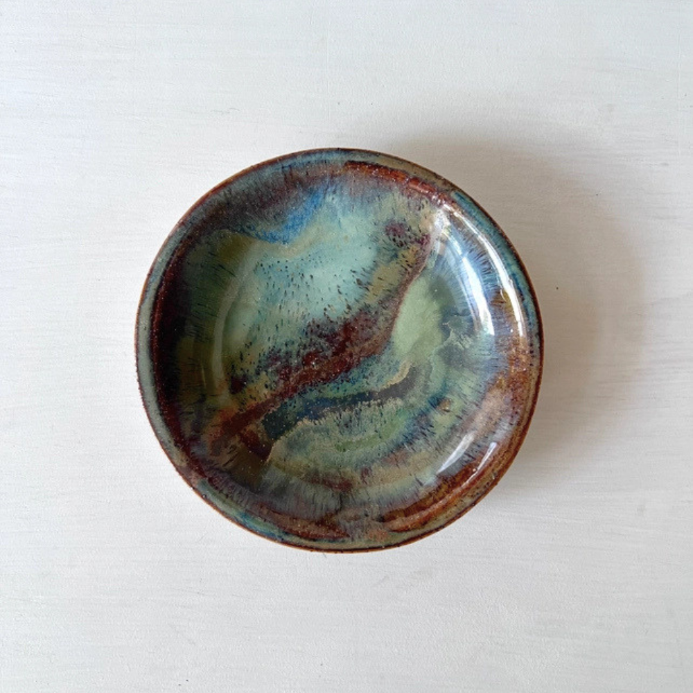 Ceramic dish with a multicoloured glaze on a white background