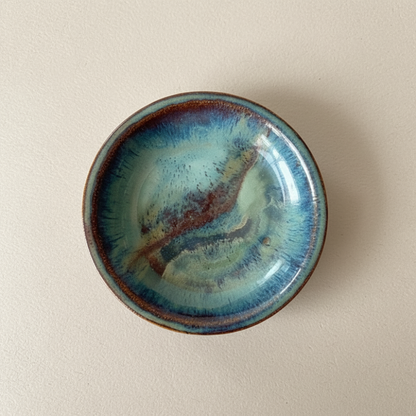 Ceramic dish with blue and brown glaze on a beige background