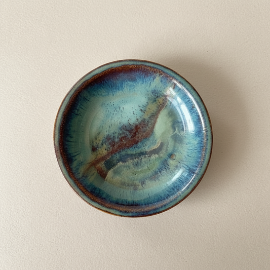 Ceramic dish with blue and brown glaze on a beige background