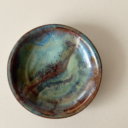 Ceramic bowl with multicoloured glaze on a beige background