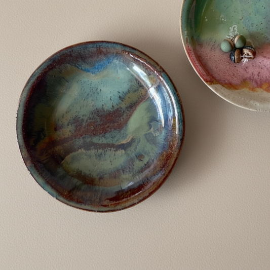 Two ceramic plates with textured glazes on a beige surface