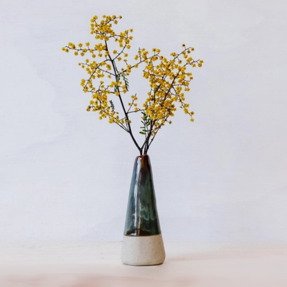 Ceramic bud vase with yellow flowers on a light background
