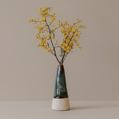 Tapered ceramic bud vase with yellow flowers on a neutral background