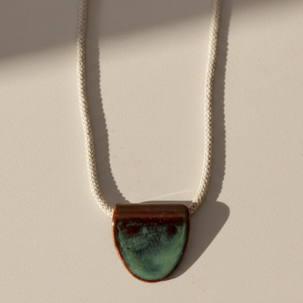 Necklace with a turquoise ceramic pendant on a beige background