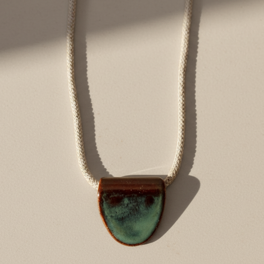 Necklace with a turquoise ceramic pendant on a beige background