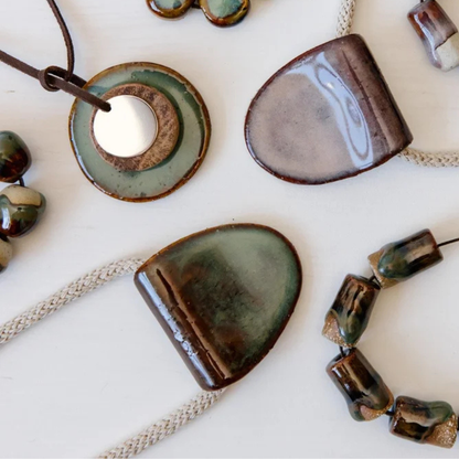 Ceramic jewellery pieces including necklaces and pendants on a light background