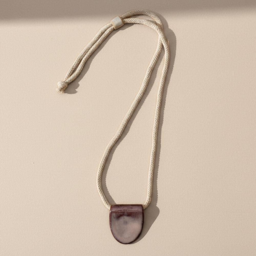 Necklace with a mulberry purple pendant on a beige background