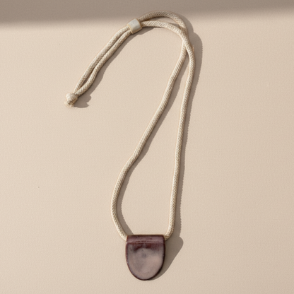 Necklace with a mulberry purple pendant on a beige background