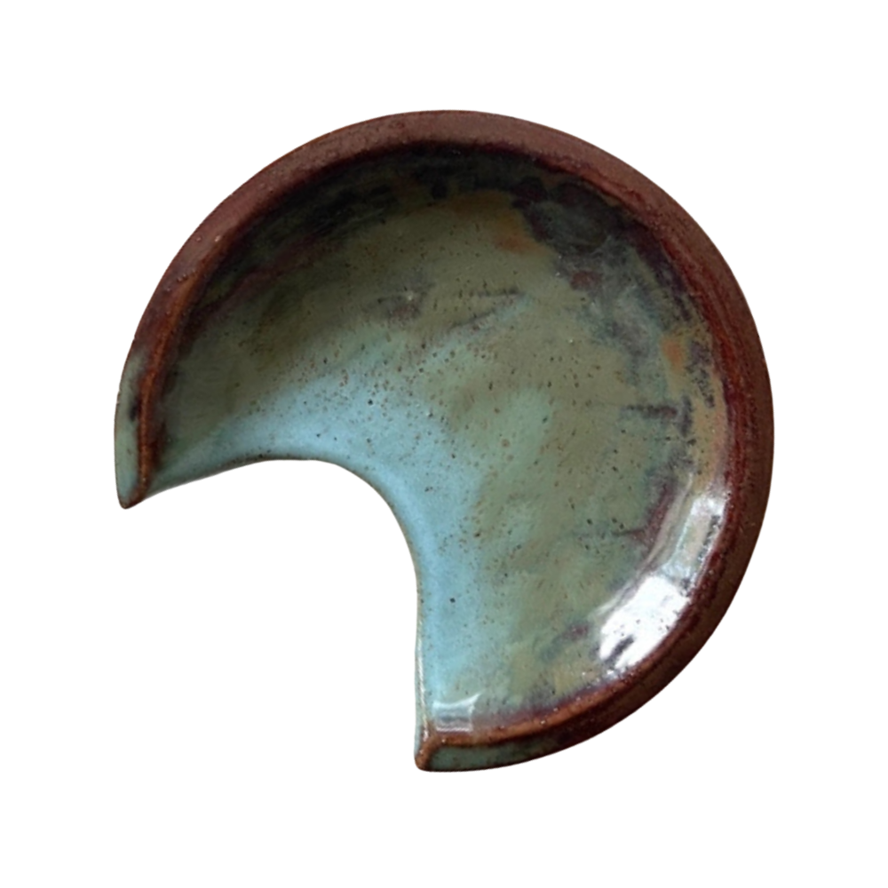 Ceramic crescent moon-shaped spoon rest with brown rim on a white background