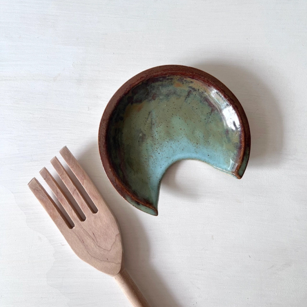 Ceramic spoon rest with a wooden fork on a white background