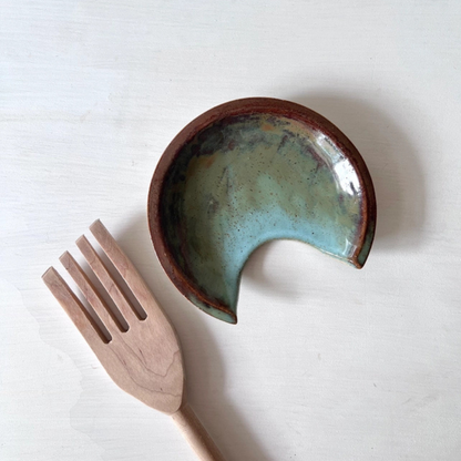 Ceramic spoon rest with a wooden fork on a white background
