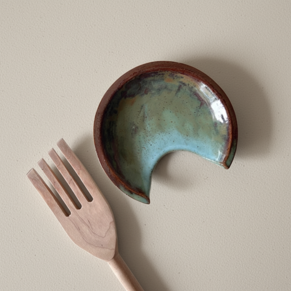 Ceramic spoon rest with a textured surface and a wooden fork on a beige background