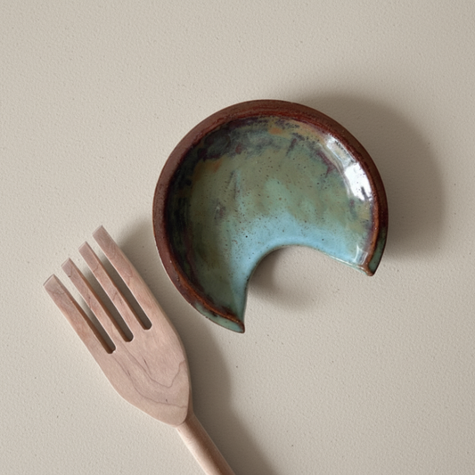Ceramic spoon rest with a textured surface and a wooden fork on a beige background