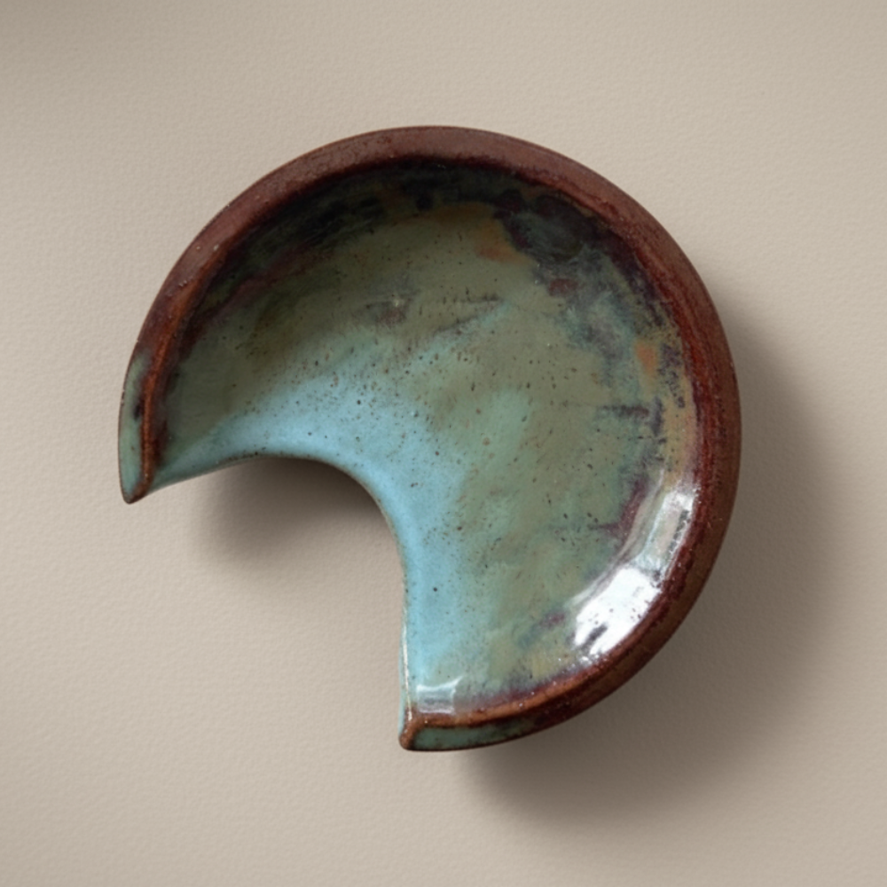 Ceramic spoon rest with a cresent shape on a beige background