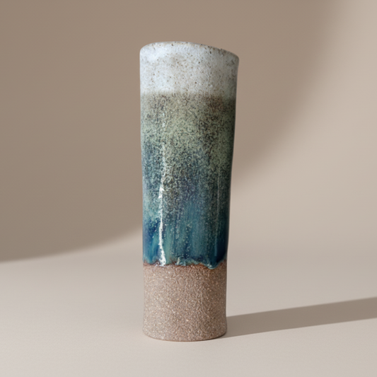 Cylindrical ceramic vase with gradient blue and beige color on a beige background