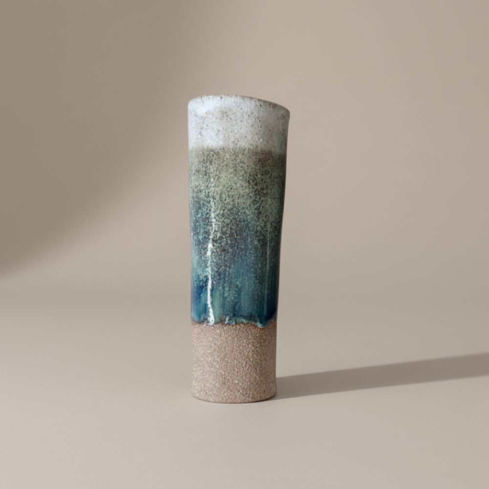 Cylindrical ceramic vase with gradient color from white to blue on a beige background