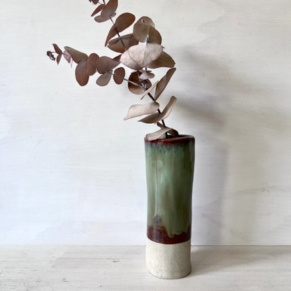 Ceramic vase with a gradient finish holding a branch against a plain background