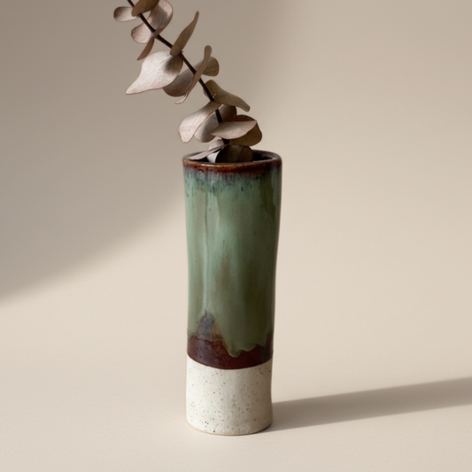 Green ceramic vase with a neutral base on a beige background